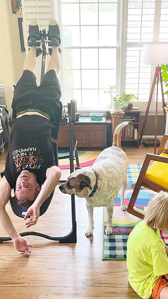 Teeter FitSpine Happy Back Club - Person Relaxing on Inversion Table with dog adjacent