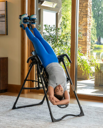 Woman using an inversion table for back stretching and relaxation in a bright room