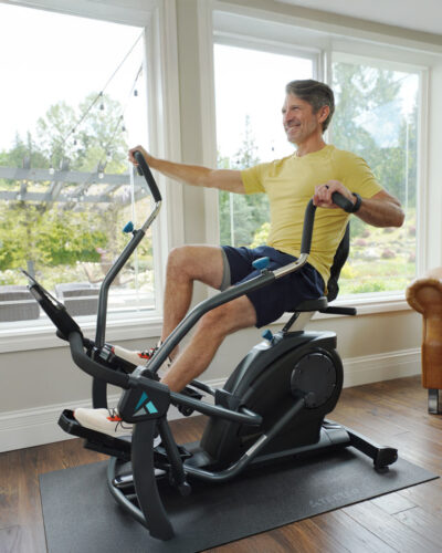 A man is seated on FreeStep Cross Trainer, focused on his workout in a well-lit room.