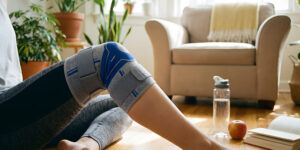 A woman sitting on the floor wearing a knee brace.