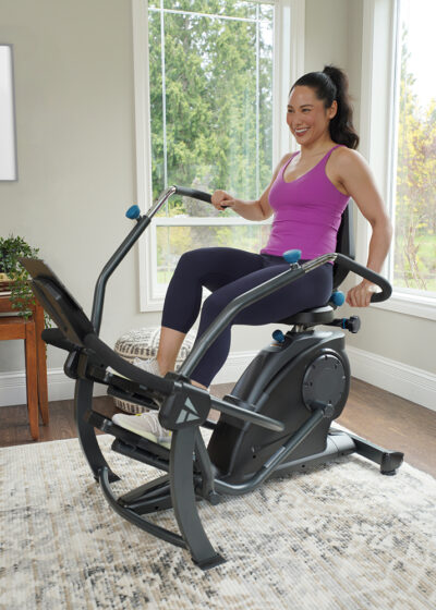 A woman on a Teeter FreeStep exercising in a bright room setting.