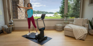 In a living room, a woman exercises, utilizing the Teeter FitForm home gym for fitness.