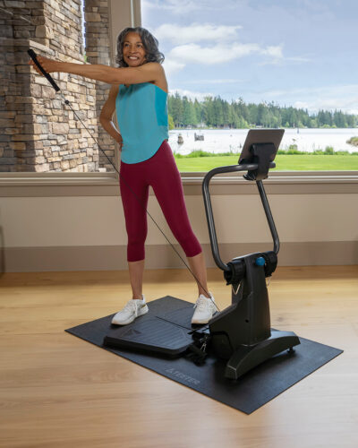 A woman is using a Teeter FitForm Home Gym in a spacious room, engaged in her fitness routine.
